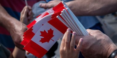 A boy reaches for a Canadian flag
