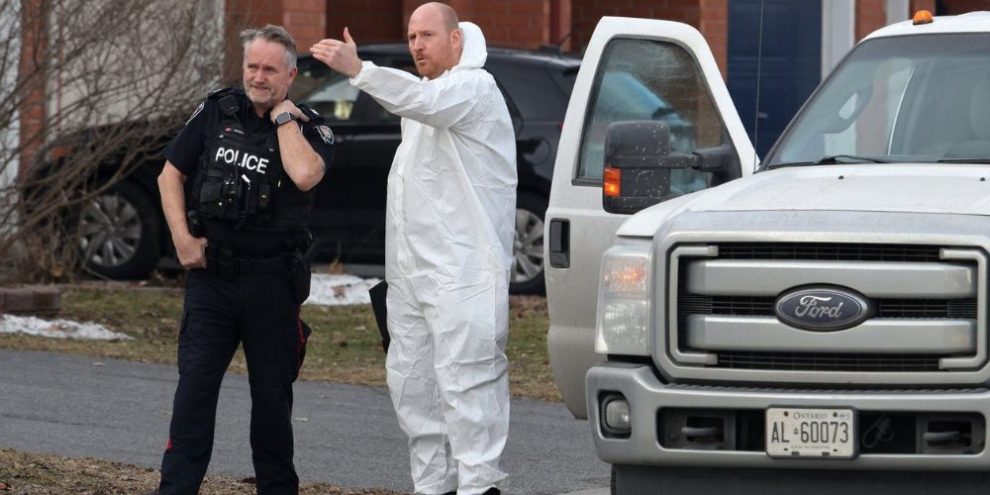 A police officer and a member of the coroner's office talk at the scene of a homicide where six people were found dead in the Barrhaven suburb of Ottawa on Thursday, March 7, 2024.