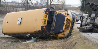 A tow truck driver works to right a school bus which rolled over south of Woodstock, Ontario on Tuesday, March 5, 2024. A child was airlifted to hospital and six other students were injured after a school bus carrying 40 children rolled over east of London, Ont., on Tuesday morning. THE CANADIAN PRESS/ Geoff Robins