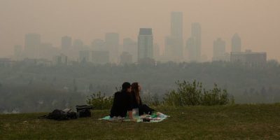 A couple sitting on a blanket overlooking smog-stricken Edmonton - CP