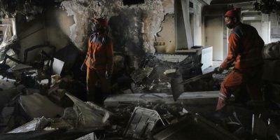Workers clear rubble of a damaged building, in Tehran, Iran