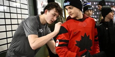 Matthew Schaefer (left) signs a Canadian hockey fan's jersey after practice in Petawawa, Ont.