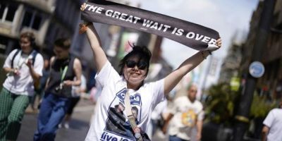 An Oasis fan holds up a banner - AP