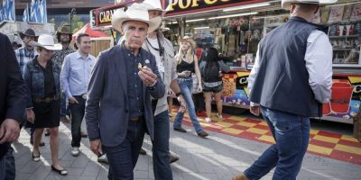 Prime Minister Mark Carney, centre, samples mini doughnuts as he walks through the Calgary Stampede grounds in Calgary