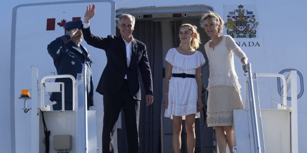 Mark Carney with his wife and daughter waving from a plane stairwell.