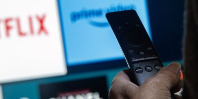 Hand holding remote in front of tv screen