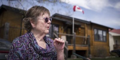 A woman in front of a house waving the Canadian flag.