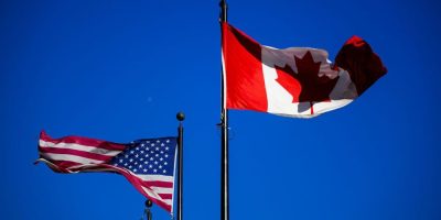 The flags of Canada and the United States fly outside a hotel in downtown Ottawa