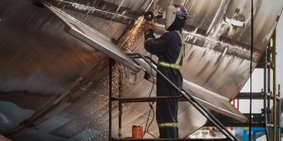 A worker uses an angle A grinder on a vessel under construction at Seaspan Shipyards