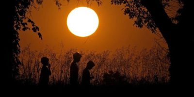 People are silhouetted against the sky at sunset as they walk at Shawnee Mission park - AP