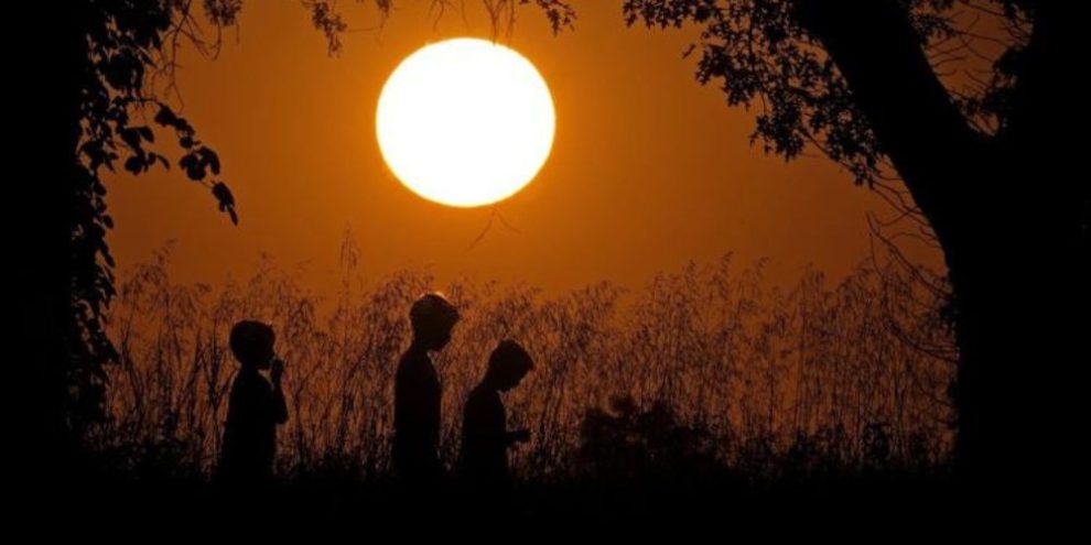 People are silhouetted against the sky at sunset as they walk at Shawnee Mission park - AP