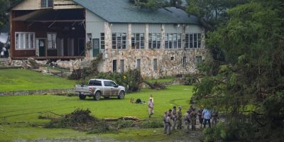 Officials search on the grounds of Camp Mystic along the banks of the Guadalupe River after a flash flood swept through the area