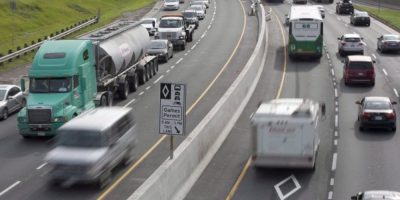 Vehicles travel quickly in the HOV lane while heavy rush-hour traffic moves slowly in regular lanes on a Toronto highway.