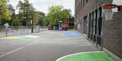 Empty schoolyard with play structures and paved areas in Montreal, photographed in the fall.