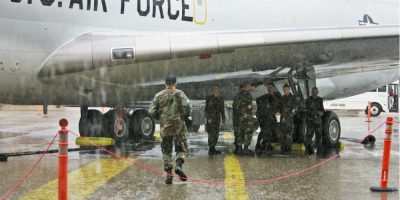 U.S. Air Force personnel stand beneath a Boeing E-3 Sentry AWACS aircraft at Tinker Air Force Base in Oklahoma during a deployment readiness setting.