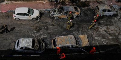 Israeli security forces inspect damage at a site struck by an Iranian missile in Petah Tikva, Israel, amid ongoing conflict with Iran and rising fuel prices.