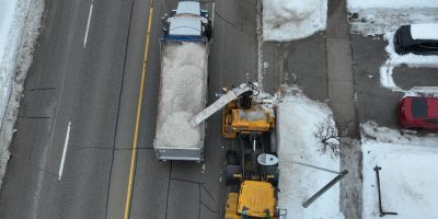 Work crews clearing large snowbanks along a street in Barrie during winter cleanup operations