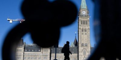 Silhouette of a man with the Peace Tower and Parliament Hill buildings in the background in Ottawa.
