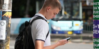 File photo of a youth using his phone while waiting to cross the street in Sydney, Dec. 8, 2025.
