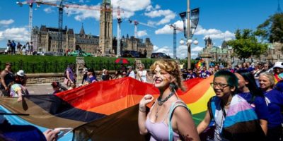 Attendees of the Capital Pride Parade hold a large rainbow flag near Parliament Hill in Ottawa on Aug. 24, 2025.