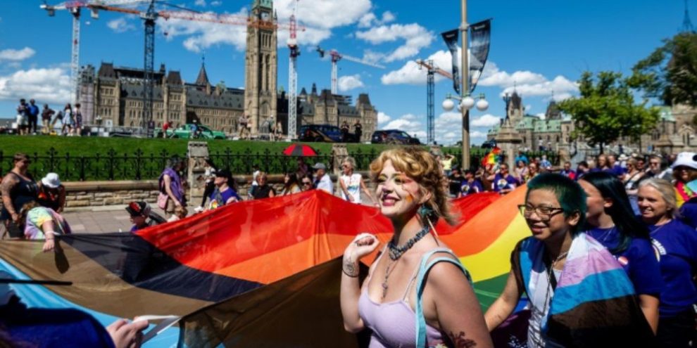 Attendees of the Capital Pride Parade hold a large rainbow flag near Parliament Hill in Ottawa on Aug. 24, 2025.