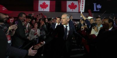 Prime Minister Mark Carney speaking at a podium during the Liberal Party national convention in Montreal, applauded by attendees in a large conference hall.