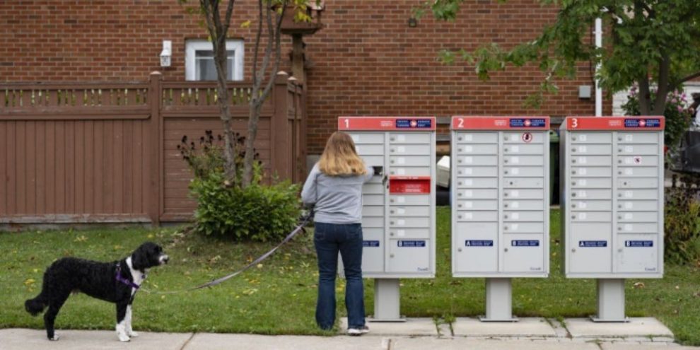 Canada Post mail truck delivering mail to a rural roadside mailbox along a country road in Canada