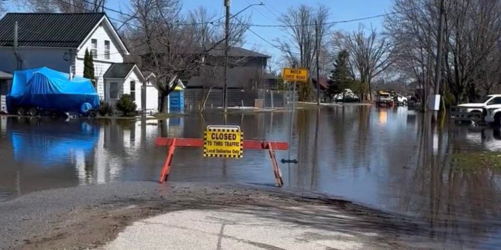 Flooded area in Orillia near Cedar Island Road with emergency sandbagging and water barriers installed along residential streets
