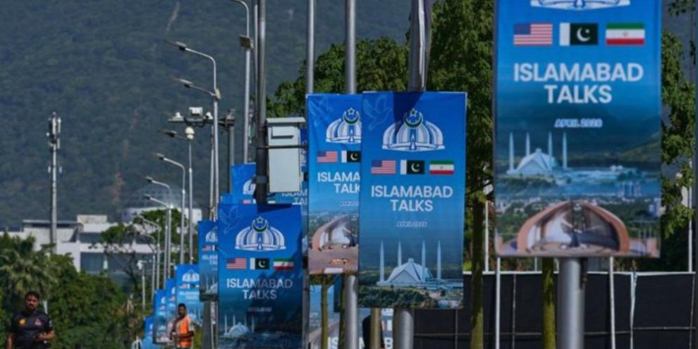Workers walk past billboards near the Serena Hotel in Islamabad ahead of U.S.-Iran negotiations