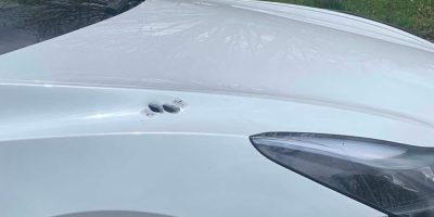 A white Tesla is parked on Hickling Trail in Barrie with two visible bullet holes in the front of the vehicle.