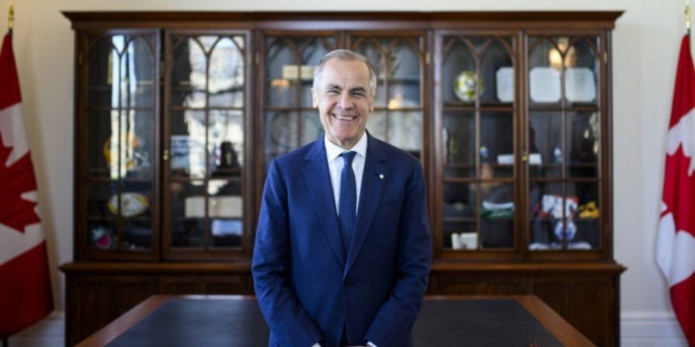 Prime Minister Mark Carney seated in his office in Ottawa, speaking about Canada-U.S. trade relations and energy policy.