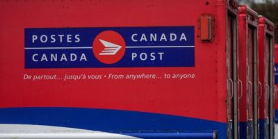 Vehicles sit idle at a Canada Post delivery depot in Burnaby, B.C., with parked postal vans lined up outside the facility.
