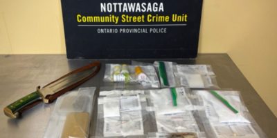 Police display suspected drugs, cash and weapons allegedly seized during a search warrant at a residence in Essa Township.