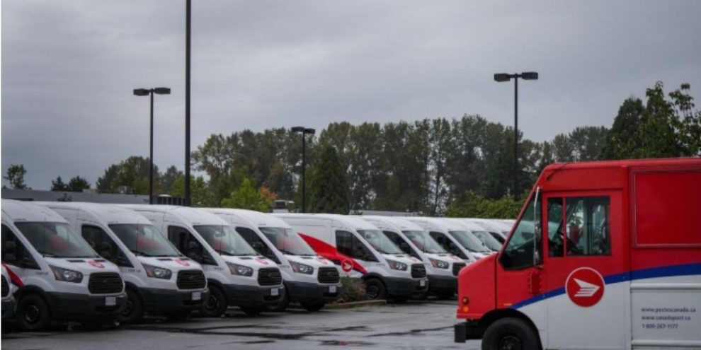 Canada Post delivery vehicles parked at a depot in Burnaby, British Columbia, as postal workers approve a new five-year collective agreement ending a lengthy labour dispute.