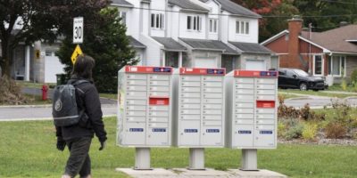 A man walks past community mailboxes in the Pointe-Claire neighbourhood of Montreal on Friday, Sept. 26, 2025. THE CANADIAN PRESS/Christinne Muschi