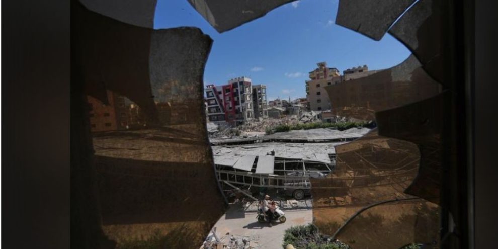 Damaged buildings in Tyre, Lebanon, are seen through shattered glass at Jabal Amel Hospital following Israeli airstrikes amid renewed fighting between Israel and Hezbollah.