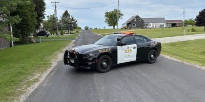 OPP cruiser blocks Concession Road 17 in Tiny Township as police investigate a rollover pickup truck crash that seriously injured one person and sent another to hospital on June 24, 2026.