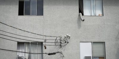 Window-mounted air conditioners and a portable unit exhaust hose installed in apartment windows on a residential building in Burnaby, B.C.