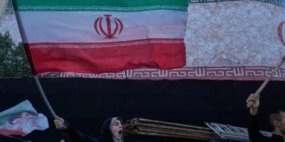 A woman waves an Iranian flag and chants slogans during a demonstration against Iran-U.S. talks at Islamic Revolution Square in Tehran, Iran, on June 14, 2026.