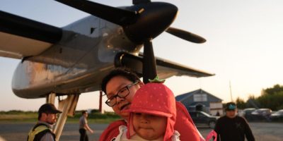 A young family boards a plane during a wildfire evacuation from Neskantaga First Nation in northern Ontario.