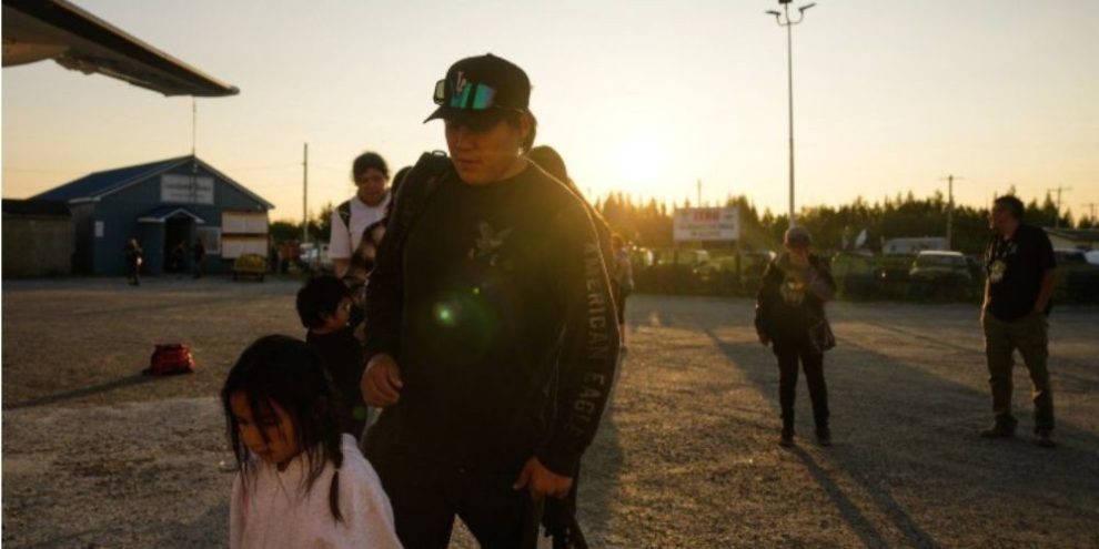 A young family boards an evacuation flight from Neskantaga First Nation during northern Ontario wildfire evacuations.