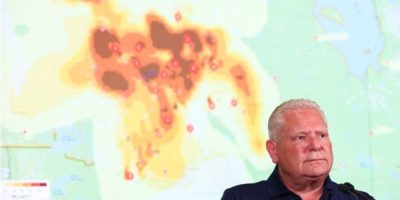 Ontario Premier Doug Ford speaks during a wildfire briefing in Toronto with a map showing smoke movement across the province.