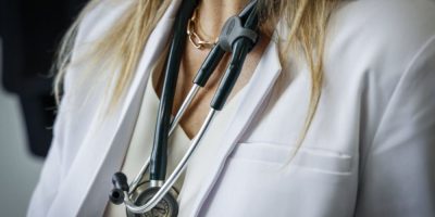Doctor wearing a lab coat and stethoscope in an exam room at a health clinic in Calgary.