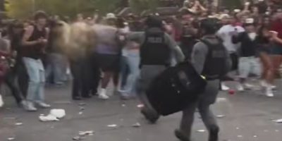 A tactical officer deploys pepper spray as crowds gather at the University of Guelph Homecoming street party.