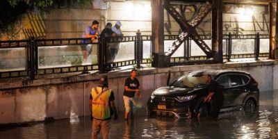 People tow a car from a flooded Toronto underpass after a severe storm
