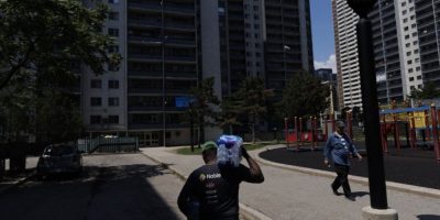 Man carries a case of water bottles between high-rise buildings in Toronto’s St. James Town