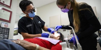 Dr. Melvin Lee performs a tooth extraction on Canadian Dental Care Plan patient Robert McFarlane at an Ottawa dental clinic.