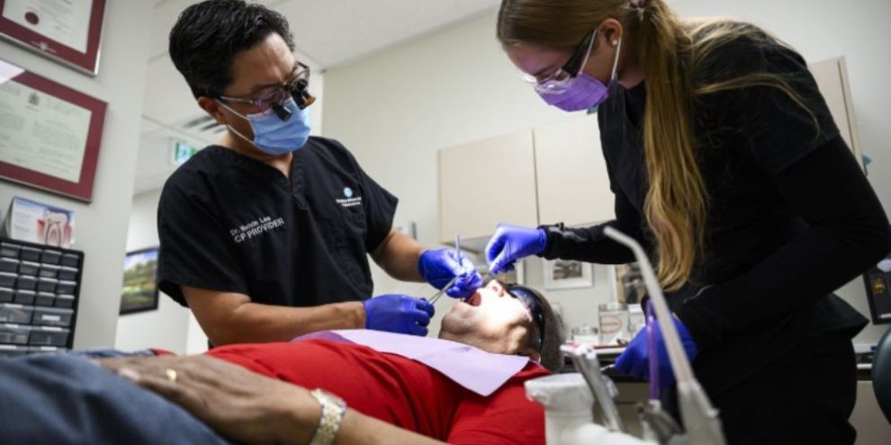 Dr. Melvin Lee performs a tooth extraction on Canadian Dental Care Plan patient Robert McFarlane at an Ottawa dental clinic.